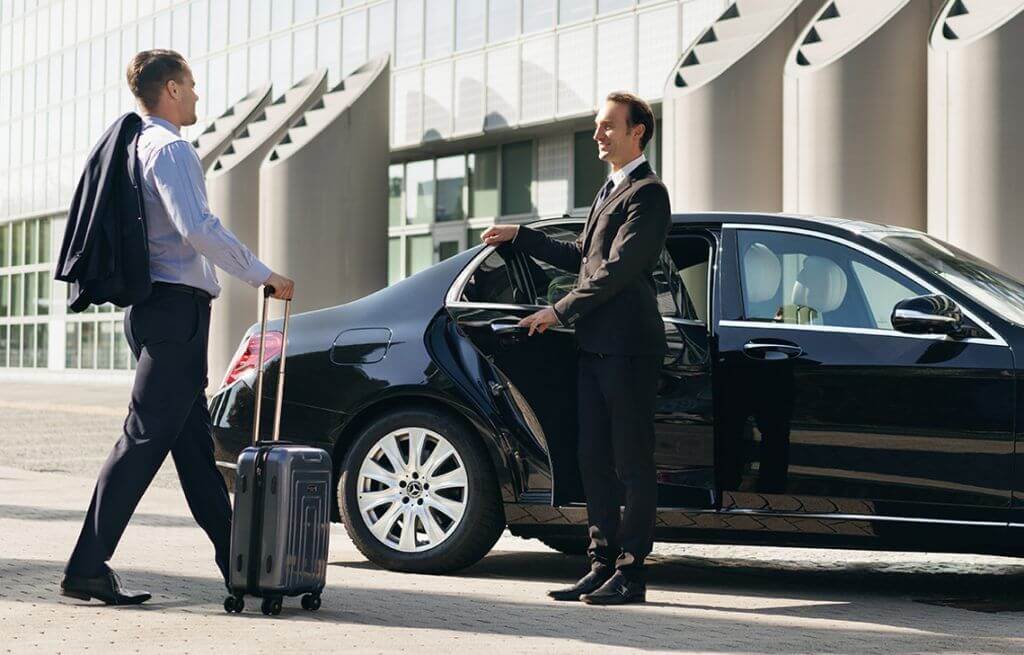 Professional chauffeur opening the door of a luxury black sedan for a business traveler, representing a premium airport transfer service in Istanbul.
