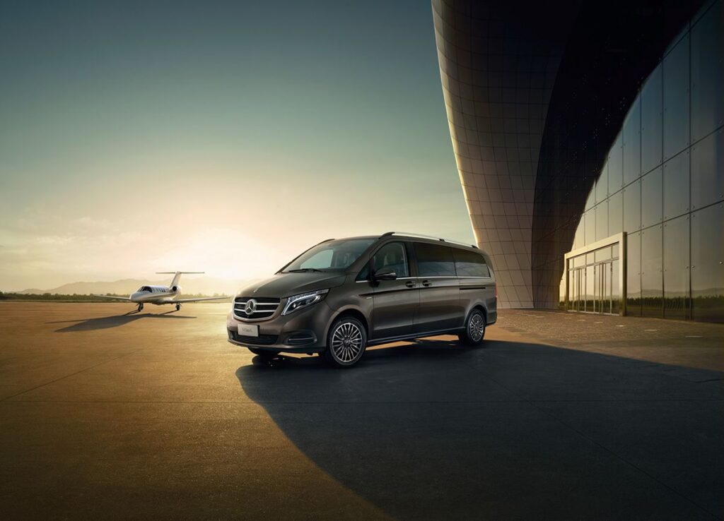 A chauffeured luxury Mercedes-Benz van providing a VIP transfer service directly from the airport tarmac next to a private jet in Istanbul.