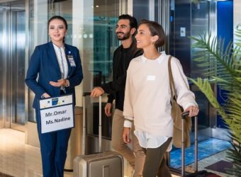 A professional female agent from Istanbul Meet and Greet Services welcoming a couple with a personalized sign at the airport terminal.